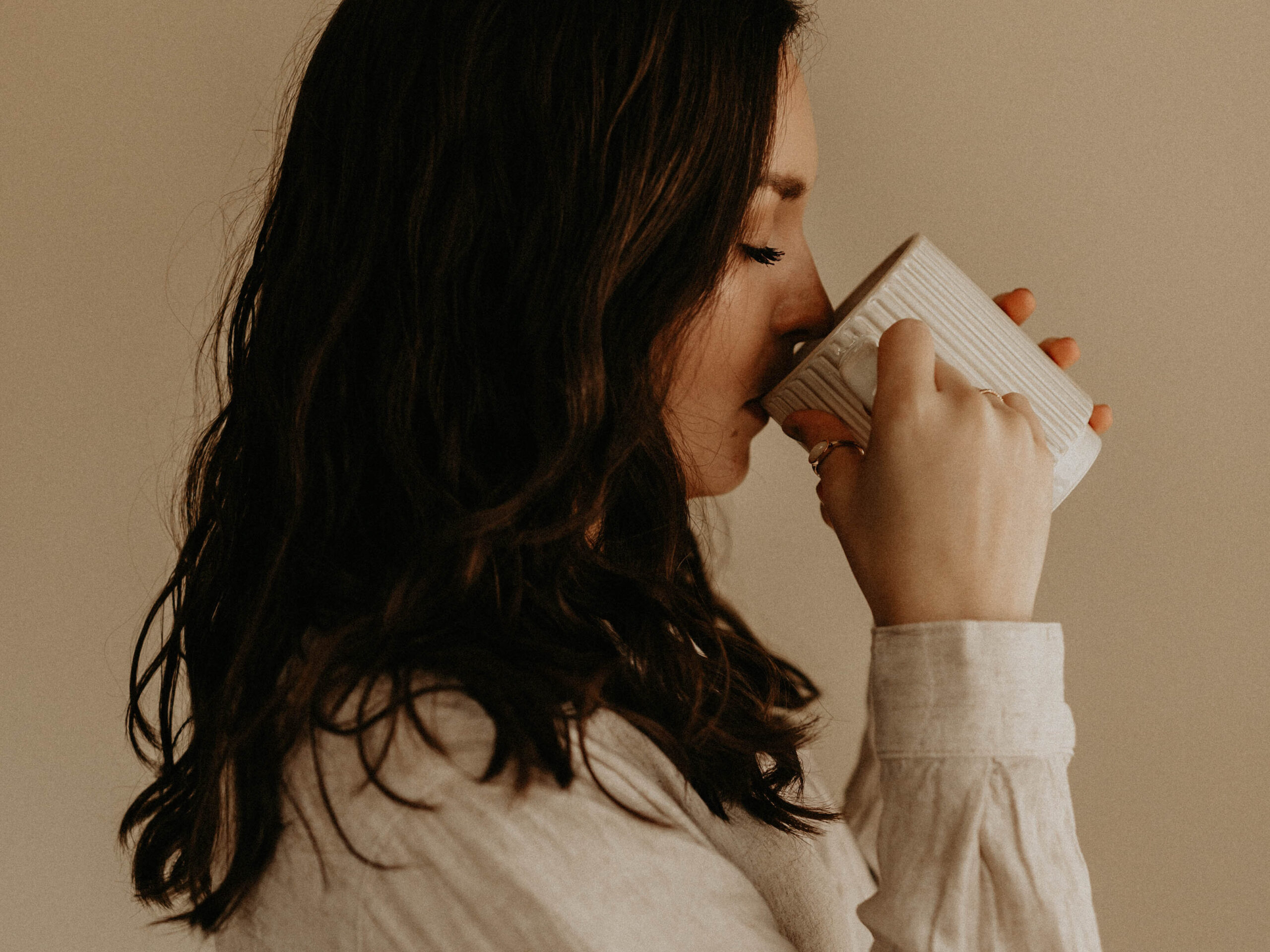 A woman sipping from a cream ribbed coffee mug.